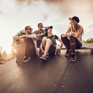 young happy friends sitting in the skate park